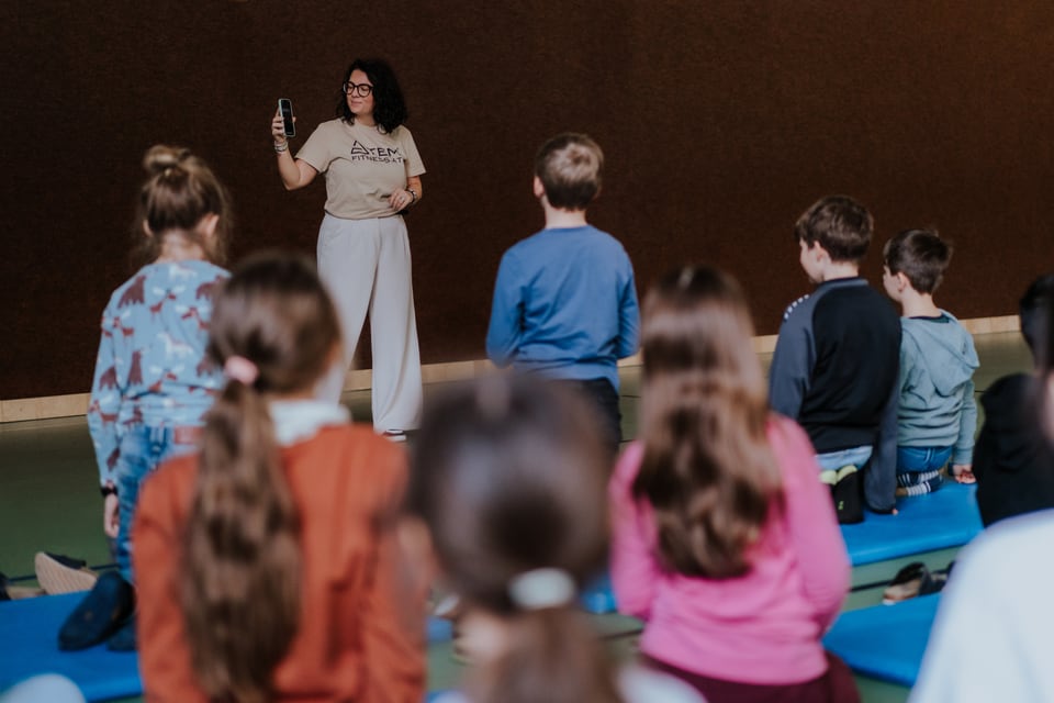 Kinder hören ihrer Trainerin im Klassenzimmer zu