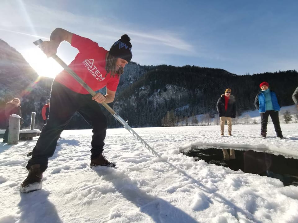 Daniel Fetzy Fetz schneidet mit einer Eissäge ein Loch in einen zugefrorenen See