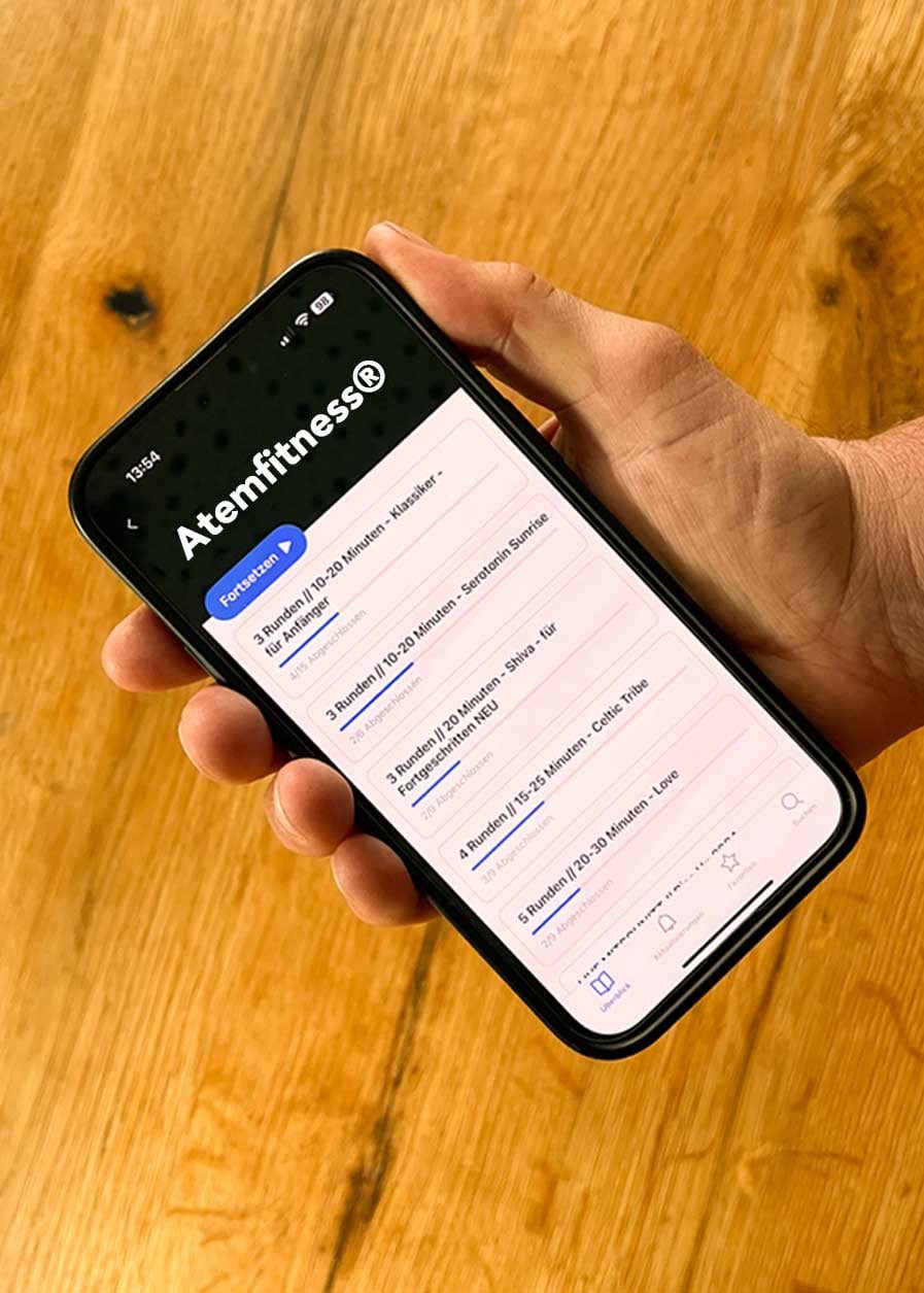 Hand hält ein Smartphone mit den Atemfitness Audios in der Kajabi App