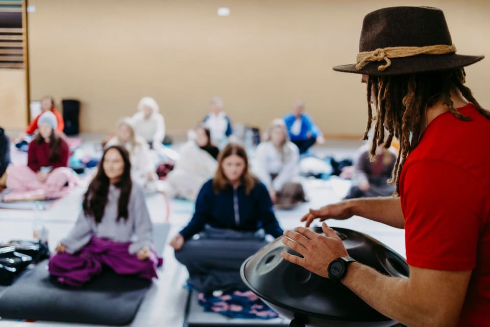 Daniel Fetz spielt Handpan vor einer sitzenden Gruppe