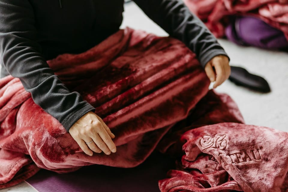 Hände ruhen während einer Atemübung auf einer roten Decke