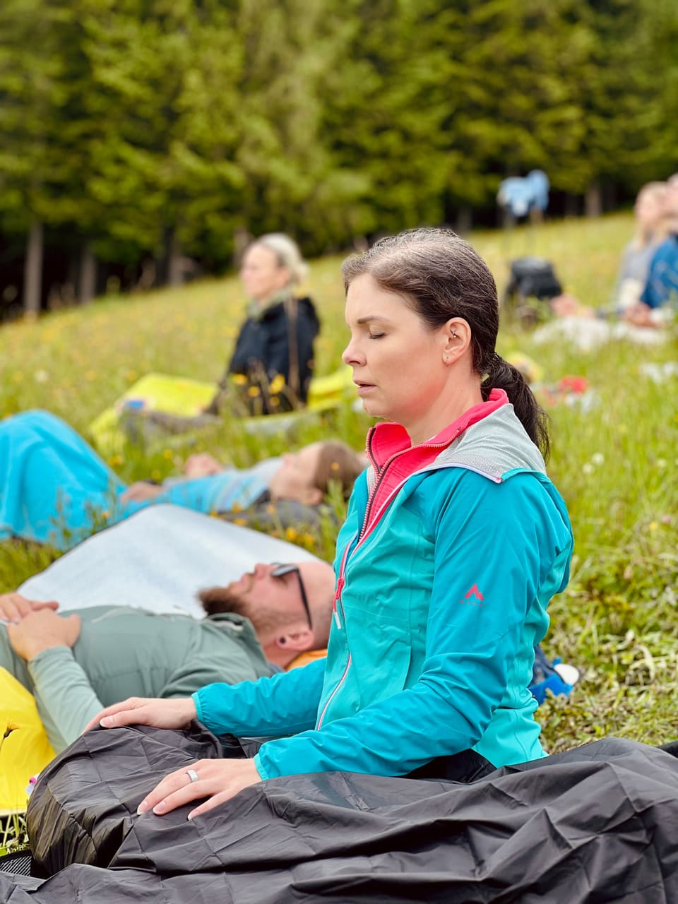 Frau meditiert während einer Atemfitness Einheit auf einer Bergwiese