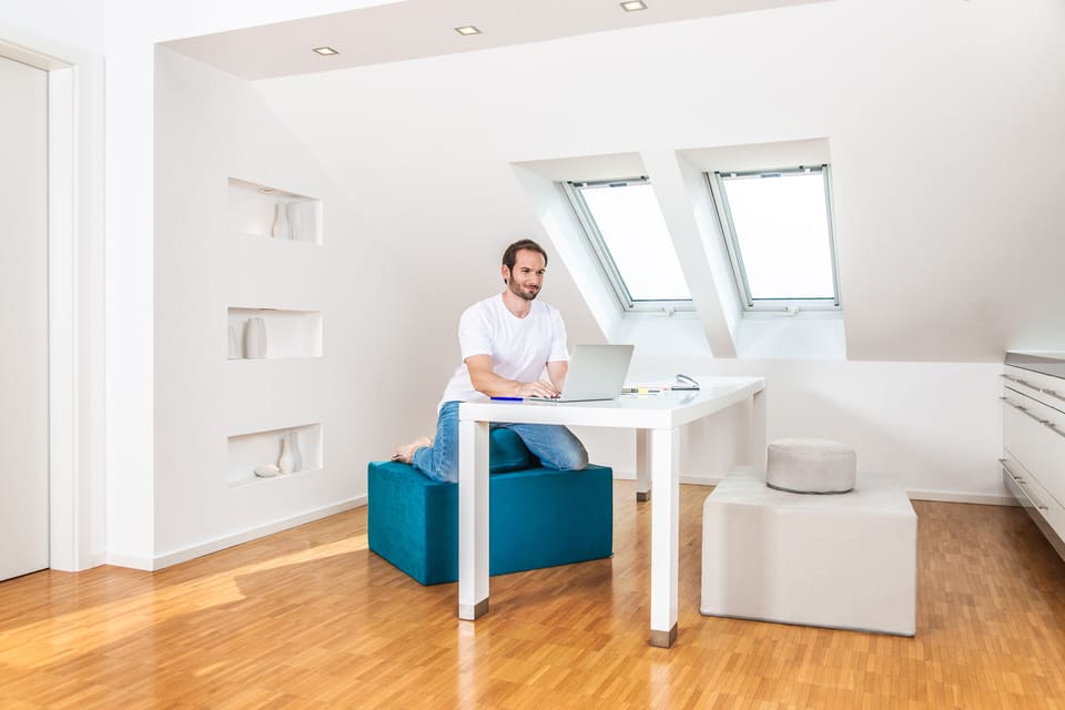 Mann sitzt kniend auf einem Paleo Chair am Schreibtisch