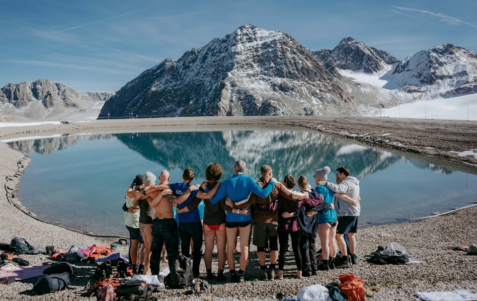 Retreat Gruppe steht Arm in Arm vor einem Bergsee im Pitztal