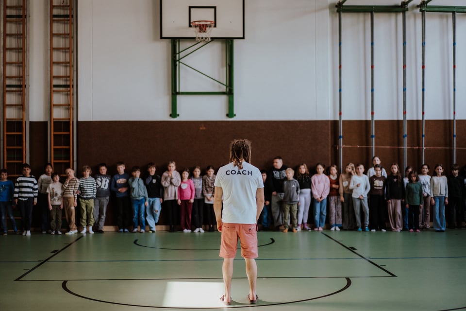 Kinder stehen mit ihrem Trainer im Kreis