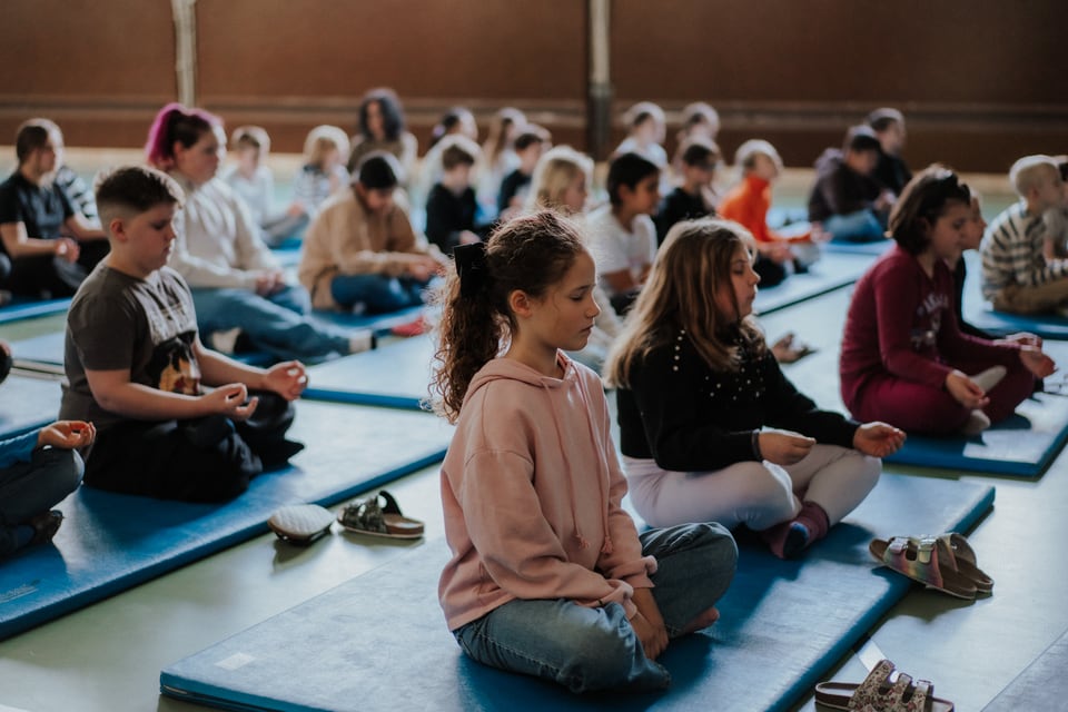 Schülerinnen und Schüler meditieren gemeinsam im Turnsaal