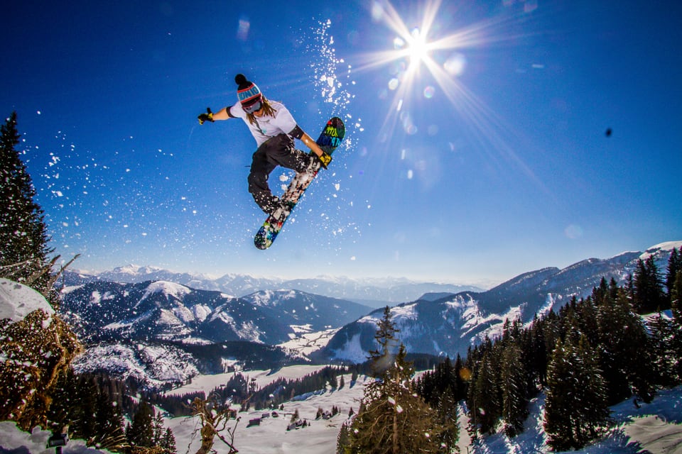 Daniel Fetz springt mit dem Snowboard vor einem verschneiten Bergpanorama